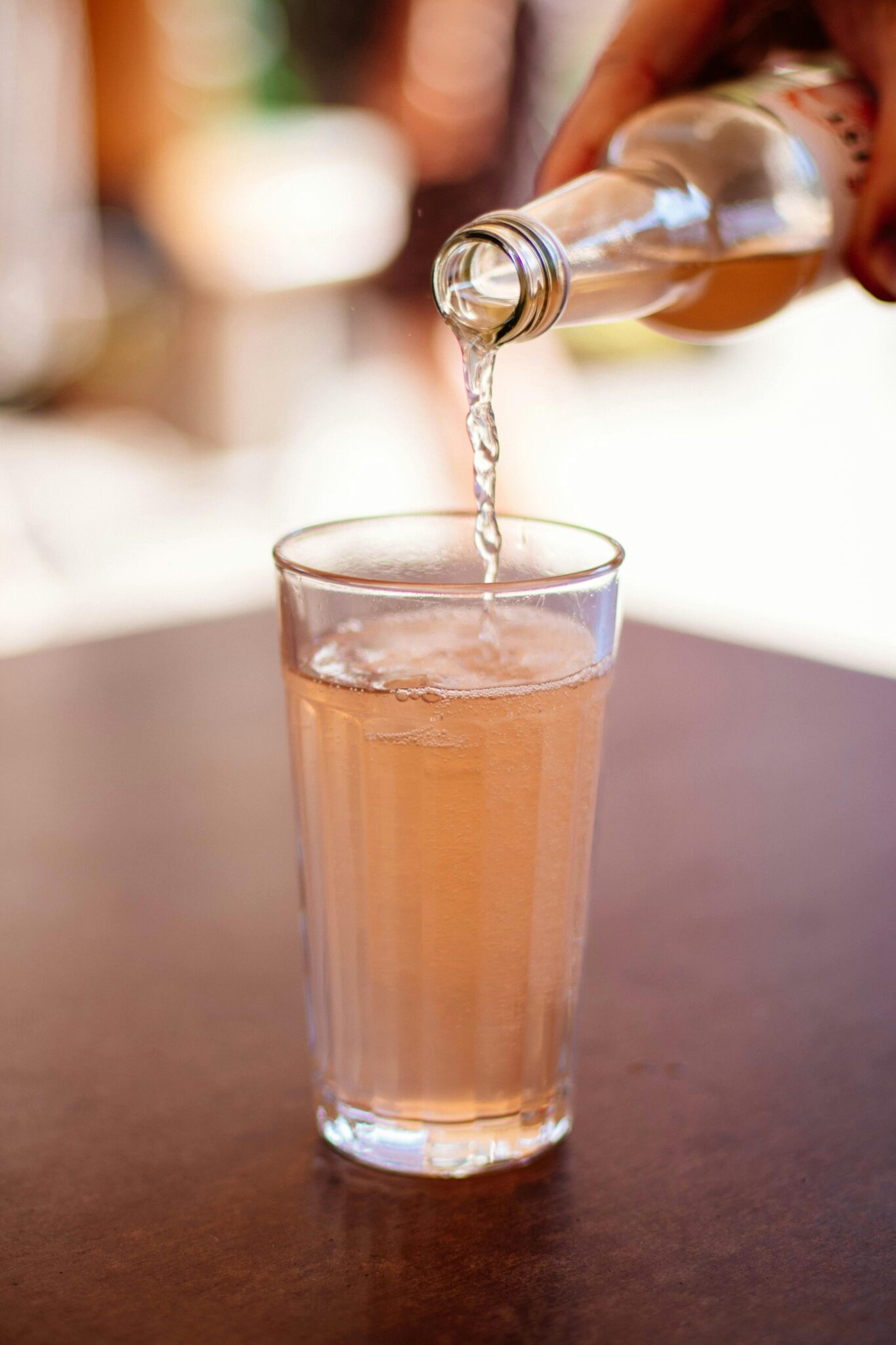 Close-up of a refreshing beverage being poured into a glass on a sunny day, perfect for summertime enjoyment.
