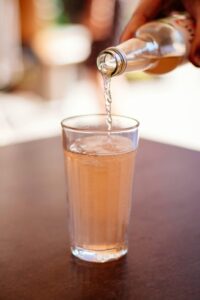 Close-up of a refreshing beverage being poured into a glass on a sunny day, perfect for summertime enjoyment.