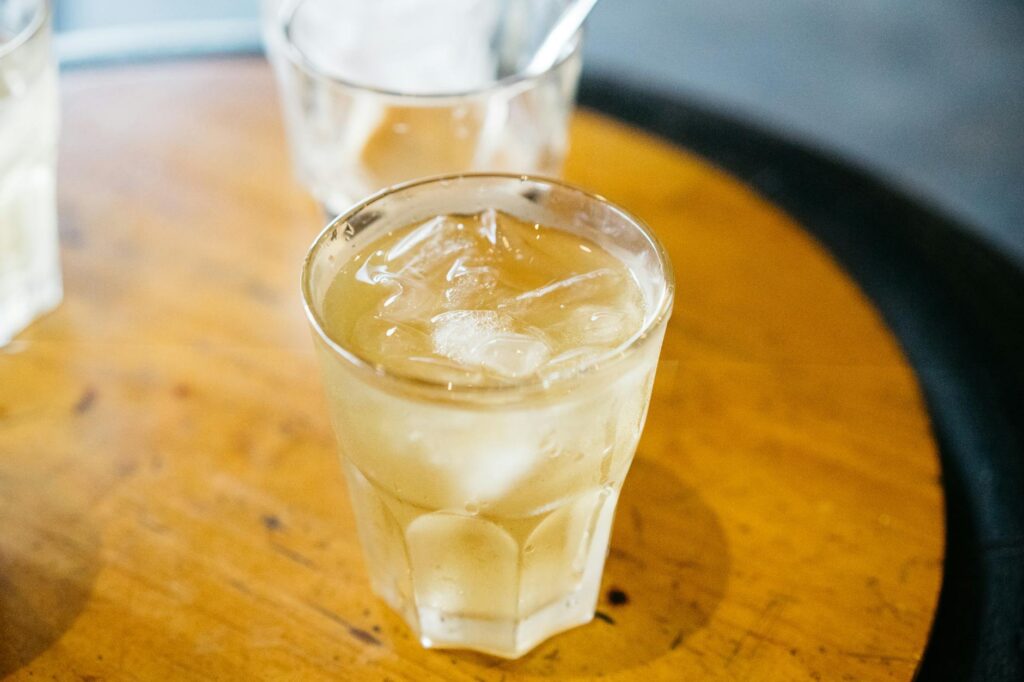 Close-up of refreshing iced tea in a glass with ice cubes on a wooden table.