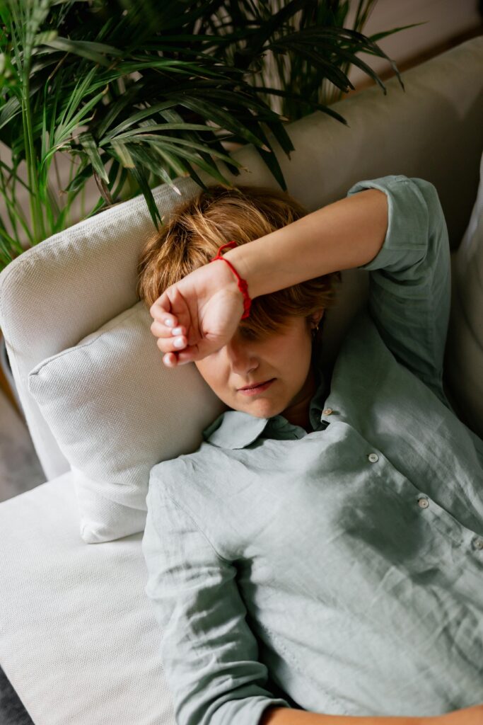 Woman resting on a sofa with plants in the background, creating a relaxed indoor atmosphere.